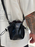Black pouch with 'Lila & Co' branding held by a person with tattoos on a white surface.