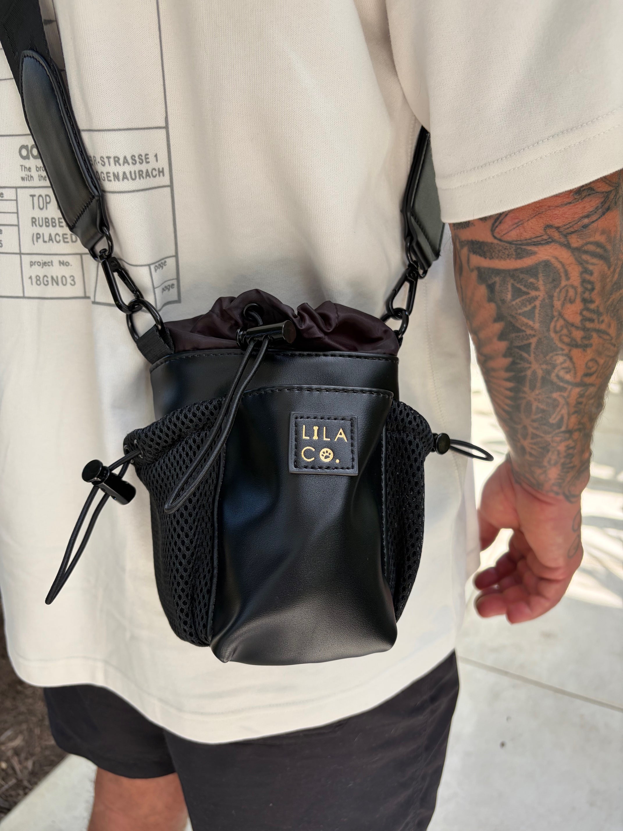 Black pouch with 'Lila & Co' branding held by a person wearing a white apron.